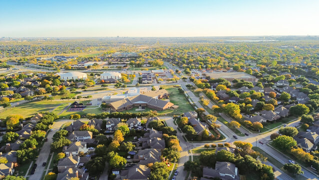 City large water tanks ground storage and elementary school in Coppell residential neighborhood with downtown Las Colinas Irving Texas in background, colorful fall foliage autumn leaves, aerial