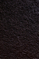 a dark-colored texture that appears as a rough and grainy surface. It may resemble asphalt or other rough surfaces.