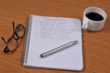 Cahier à spirales sur lequel est écrit en français avec un stylo bonnes résolutions