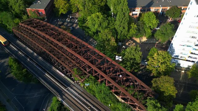 Yellow S Bahn train crossing metal bridge at Former border Berlin, germany. Dramatic aerial view flight drone camera pointing down
