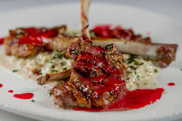 lamb chop stick grilled with red cherry sauce setted with porridge and topped with seasonal herbs, served on white plate and background cloth