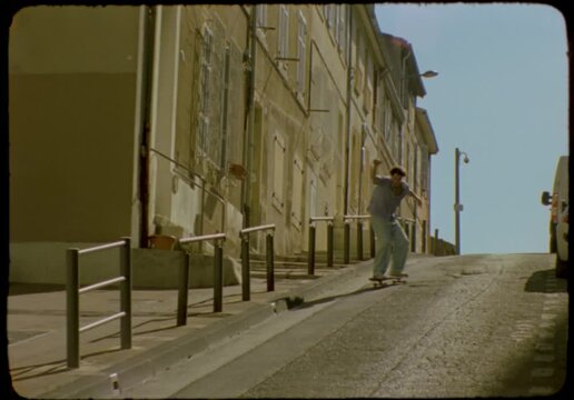 Vintage 16mm film of a young man skateboarding down a city street, Marseille, France