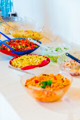 Colorful Selection of Fresh Salads and Pasta on Buffet Table at Event Catering With Spoons Ready for Serving and Enjoyment