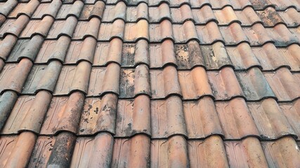 A detailed close-up view of weathered clay roof tiles, showcasing their aged texture, earthy tones, and natural patterns formed over time.
