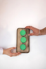 Green macaroons. Sweets. Pink filling for macaroons. Delicious pastries. Hands take macaroons