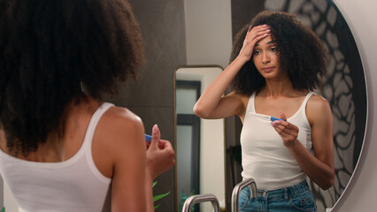 Worried scary afraid anxious African American woman girl in bathroom looking on positive pregnant...