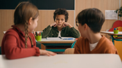 Multiracial diverse noisy little classmates multiethnic students pupils people children diversity kids friends noisy talking in school class at lesson sitting at table education learning studying talk