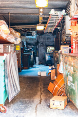 Industrial Warehouse Interior with Cardboard Boxes and Waste Containers in a Dimly Lit Urban Alley,...