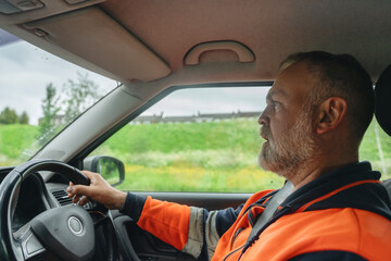 Surveyor driving to place of work through a rural landscape with greenery and overcast sky in the background