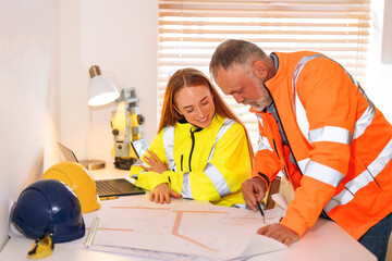Construction workers manager and site engineer collaborate on project plans while reviewing...