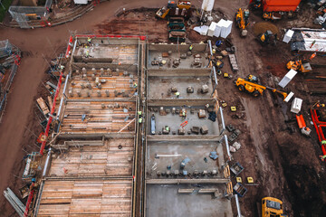 Aerial view from sky at construction site showing building progress with equipment and materials in...
