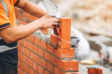 Bricklayer laying bricks with trowel at a construction site during daylight hours