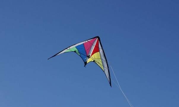 cometa multicolor volando al viento bajo un cielo azul despejado nitido luminoso