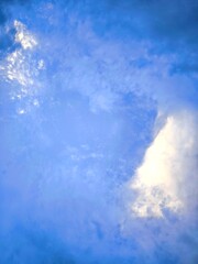 Sunlight, clouds on the background of the morning sky. Blue, white sky in pastel colors, sun glare from a soft-focus lens. Abstract blurred blue gradient on the background of peaceful nature.