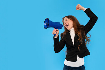 Young woman celebrates with a megaphone against a bright blue background, expressing joy and...