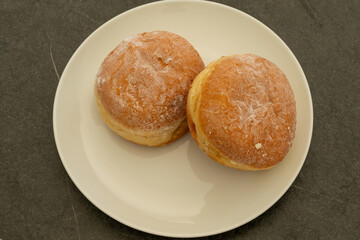 Two delicious berliner doughnuts on a white table on black background.