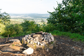 Obraz premium Fireplace in the woods at a beautiful vantage point, with a view over the country. No fire burning yet, but the place is ready and some fire wood is already close by.