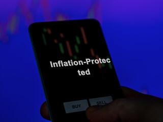 An investor analyzing the inflation-protected etf fund on a screen. A phone shows the prices of Inflation-Protected