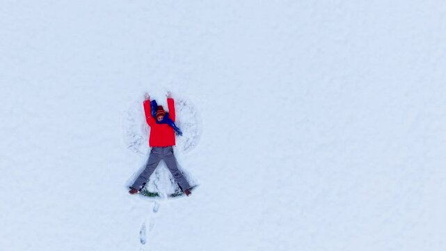 Woman making snow angel in winter wonderland under clear sky