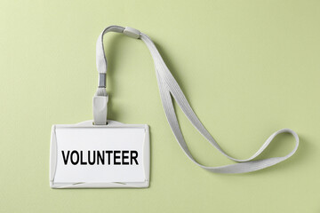 Badge with word Volunteer on light green background, top view
