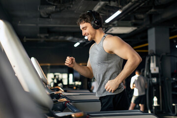 Sporty man exercising in gym, running using treadmill machine equipment, healthy lifestyle and cardio exercises at fitness club