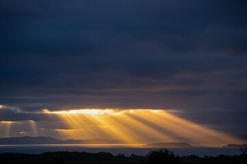 Spectacular sun rays over coast from distance