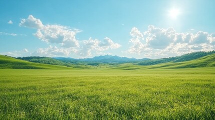 Fototapeta premium A vast green landscape under a bright blue sky, featuring rolling hills, distant mountains, and fluffy white clouds.