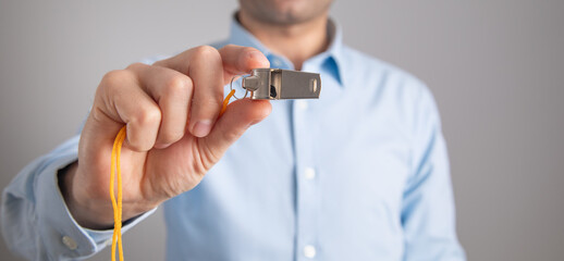 Referee or trainer holding a metal whistle.