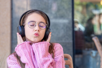 Happy teenage girl in headphones listening to music. Emotions concept.