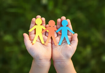 Child Holding Paper People Depicting Unity in Diversity, Social Protection, and Building a Happy Family Environment