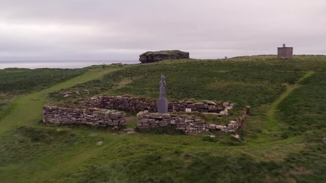 Aerial close-up past St. Patrick statue to Dun Briste sea stack at Downpatrick Head, Ireland