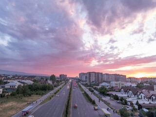 Drone view of city at sunset. Beautiful clouds on the sky. Bright evening golden, pink and blue...