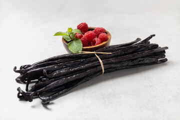 Vanilla beans with raspberries on gray background