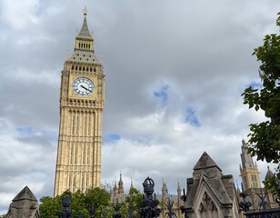 Big Ben towering above the houses of parliament against a cloudy sky in Westminster, London, UK. 