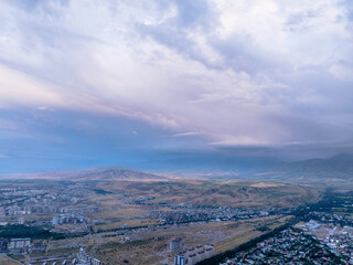 Drone view of the town and mountains before the rain. Large clouds on the sky. Evening cityscape.