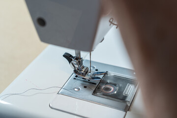 Detail of the needle, foot and presser foot of a household sewing machine.
