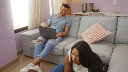 Man and woman in a living room with a laptop, depicting everyday life in a cozy apartment with a casual and relaxed atmosphere