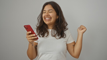 Young hispanic woman smiling and holding smartphone isolated against white background