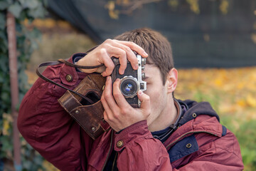 A young man takes pictures on a vintage camera. Film camera photography.