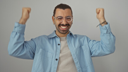 Young, hispanic, man with glasses and moustache smiling and raising his arms in celebration over isolated, white background