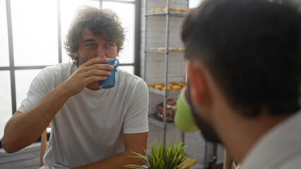 Men drinking coffee together in a cozy bakery, showing friendship in an indoor setting with a warm and inviting atmosphere.