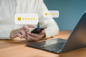 Person using a smartphone to leave a five-star review, with floating feedback icons and a laptop on a desk, symbolizing online reviews, testimonial and customer satisfaction.