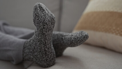 Woman relaxing indoors with cozy socks on comfortable couch at home living room setting with soft cushions in view.