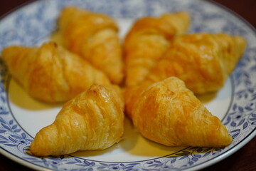 Five pieces of butter croissants on a white plate with a blue pattern.