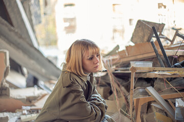 A woman near a house destroyed by the war. War in Ukraine.