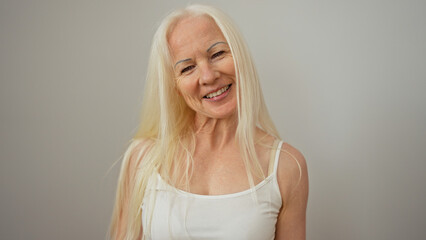 Woman with albinism smiling in front of white wall, showcasing blonde hair and caucasian middle-aged features in an isolated environment.