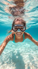 Fototapeta premium Young girl enjoying a joyful swim underwater in clear blue water