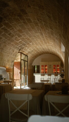 Rustic restaurant interior with stone arch ceiling, white chairs, wooden tables, bar counter, wine bottles, and soft ambient lighting creating a cozy atmosphere