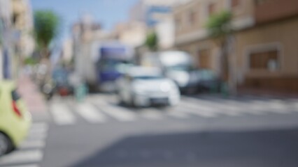 Out-of-focus street scene with blurred vehicles and urban buildings on a sunny day in a city