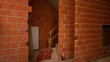 Blurred construction site with unfinished brick walls, scattered materials, and yellow staircase in background.